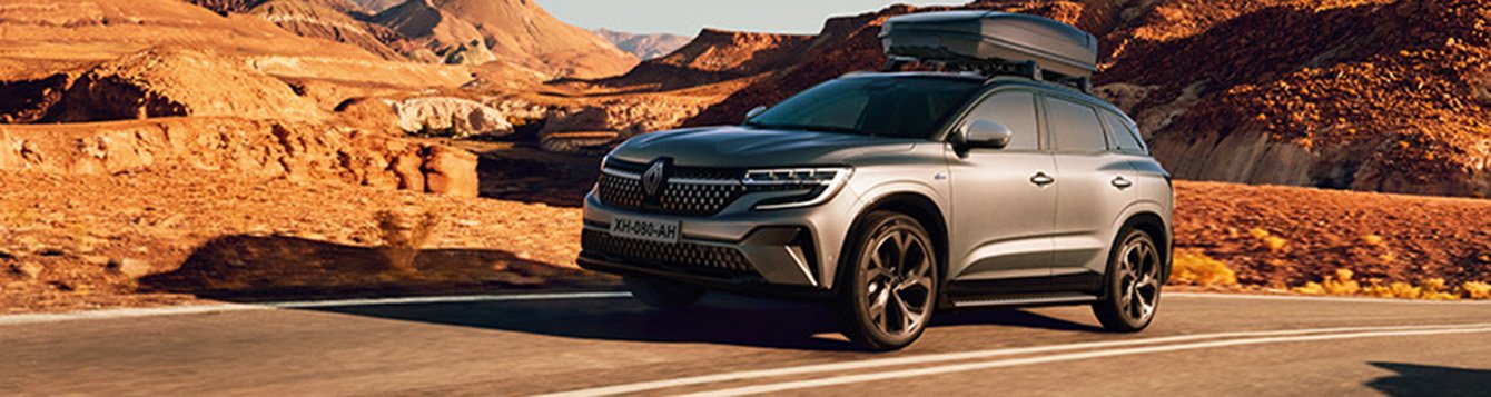 Renault SUV fährt auf einer Straße durch eine beeindruckende Landschaft mit Bergen und Felsen.