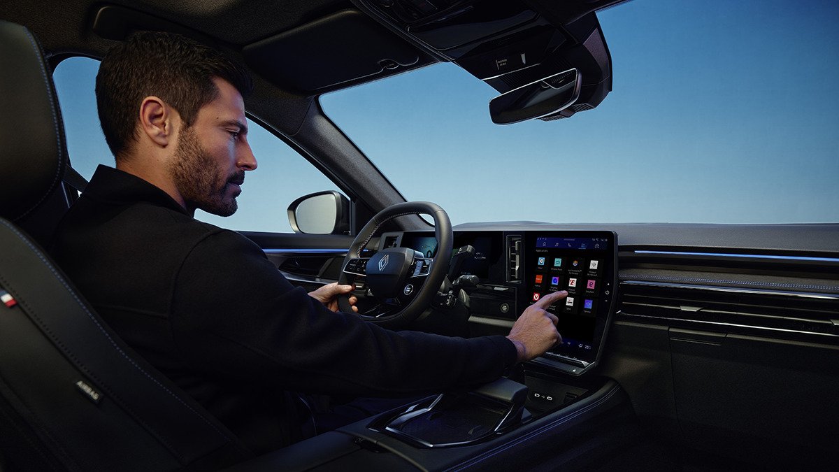 Mann im Auto bedient das Infotainment-System über einen Touchscreen in der Mittelkonsole.