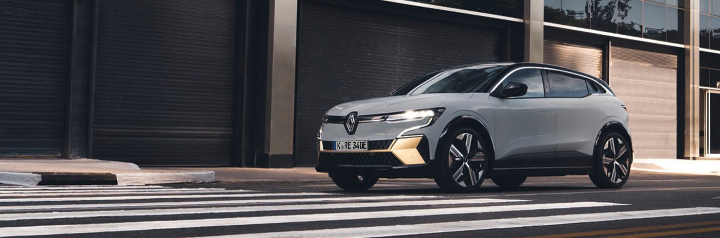 Ein moderner Renault Elektro-SUV parkt auf einem Zebrastreifen vor einer urbanen Kulisse.