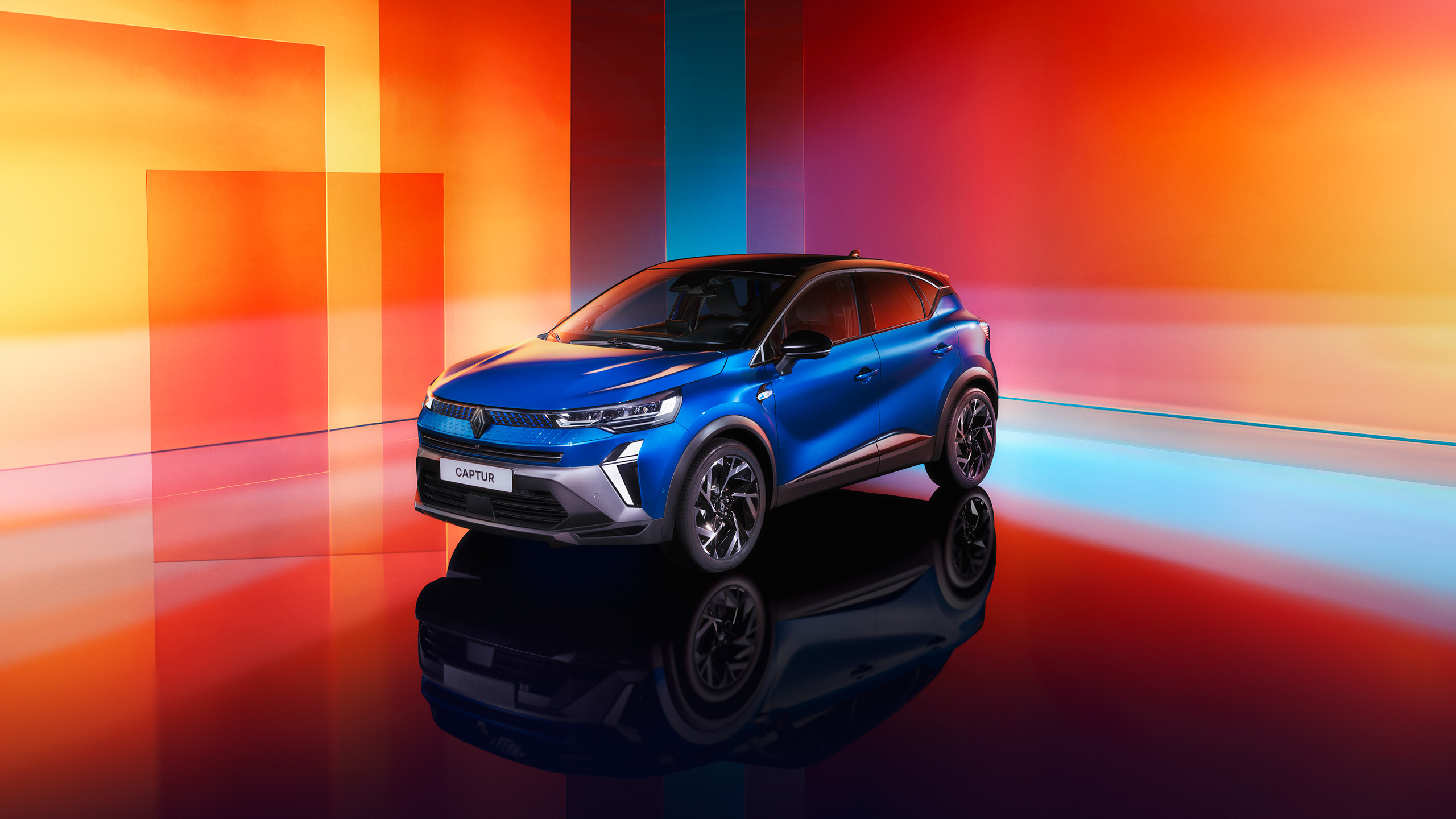 Renault Captur in leuchtendem Blau vor einem bunten Hintergrund aus geometrischen Formen.