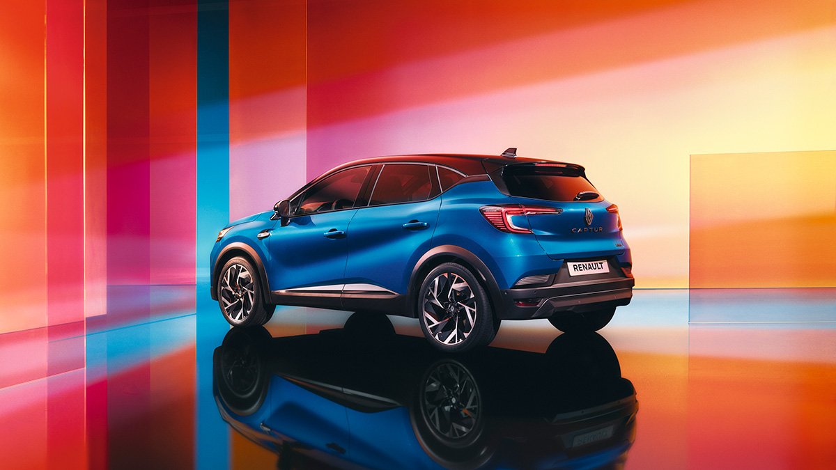 Ein blauer Renault Arkana SUV vor einem bunten, reflektierenden Hintergrund in Orange- und Pinktönen.
