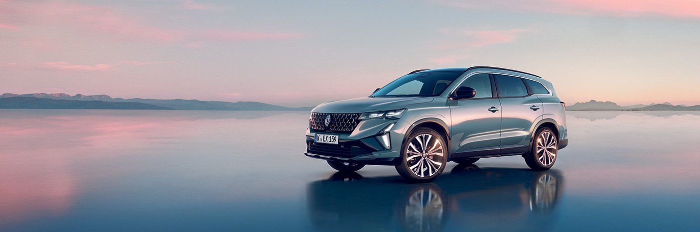 Ein modernes SUV steht am Wasser vor einem farbenfrohen Himmel, ideal für Outdoor-Abenteuer.