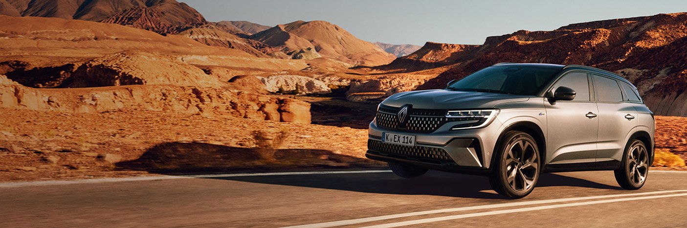 Ein silberner Renault SUV fährt auf einer Straße durch eine trockene, bergige Landschaft.