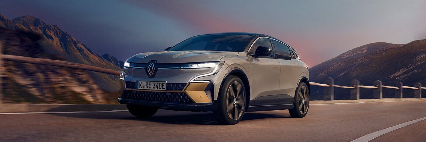 Ein Renault Elektroauto fährt auf einer malerischen Bergstraße bei Sonnenuntergang.