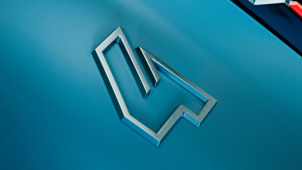 Detailaufnahme eines silbernen Logos auf einer blauen Oberfläche, moderne Automobildesign.