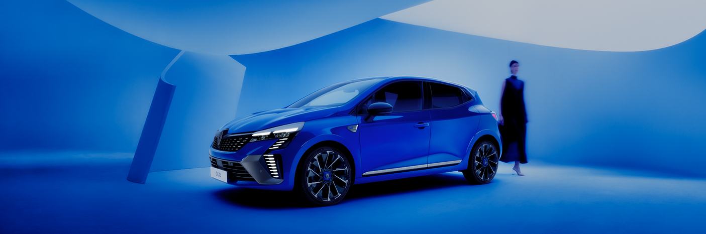 Ein blauer Renault in einem modernen, blauen Studio mit einer Person im Hintergrund.