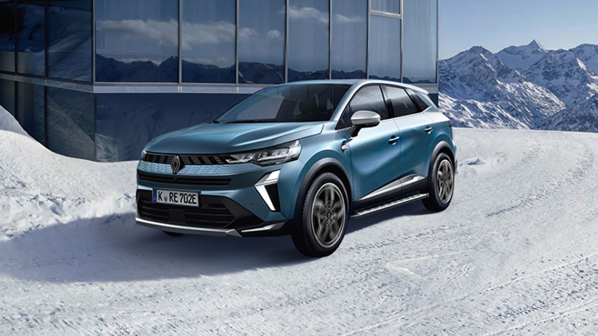 Ein blauer SUV von Renault parkt auf Schnee mit Bergen im Hintergrund, ideal für winterliche Abenteuer.