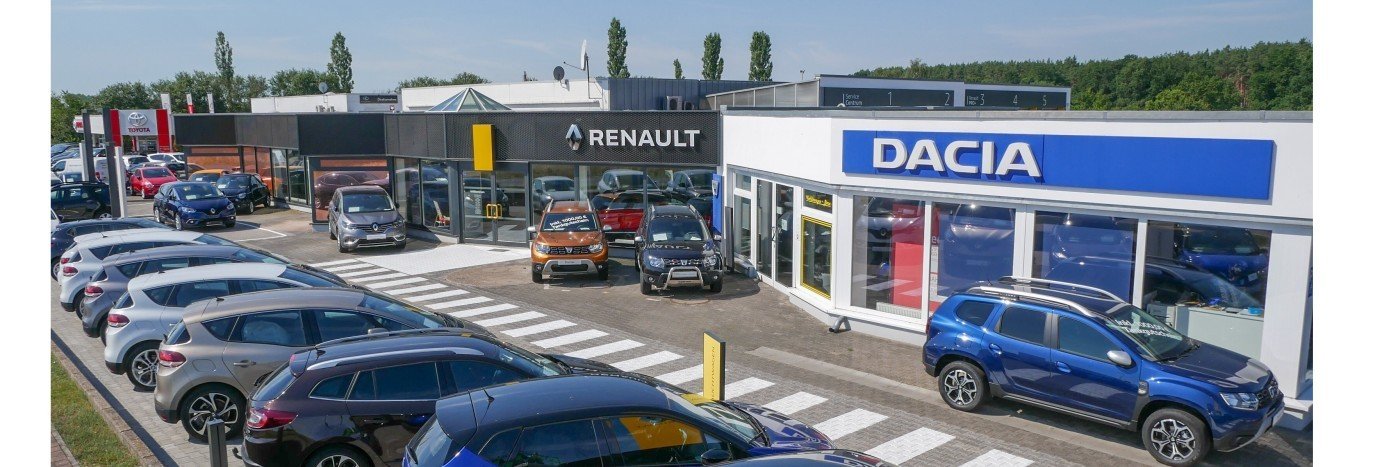 Renault- und Dacia-Autohändler mit mehreren Fahrzeugen auf dem Verkaufsplatz und sauberer Parkplatzansicht.