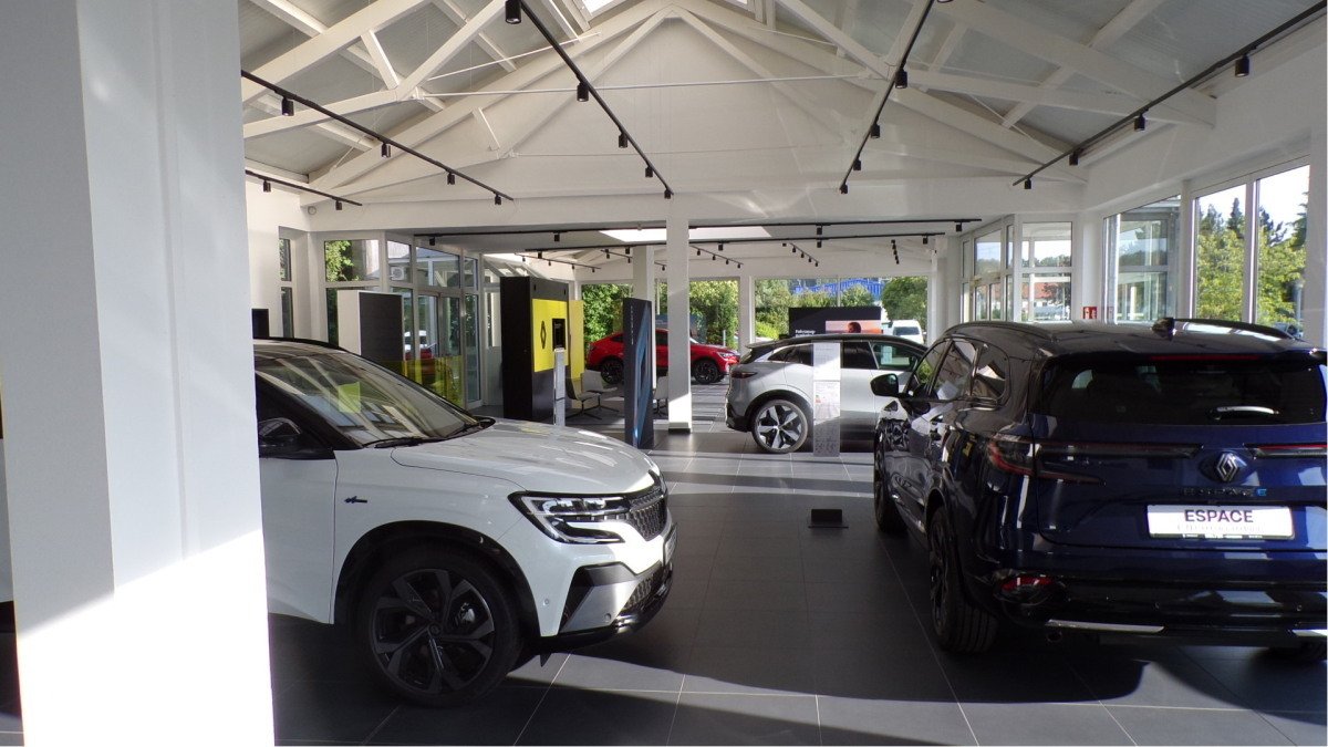 Moderne Autohalle mit mehreren Fahrzeugen, darunter ein weißes und ein schwarzes Modell, in hellem, offenem Raum.