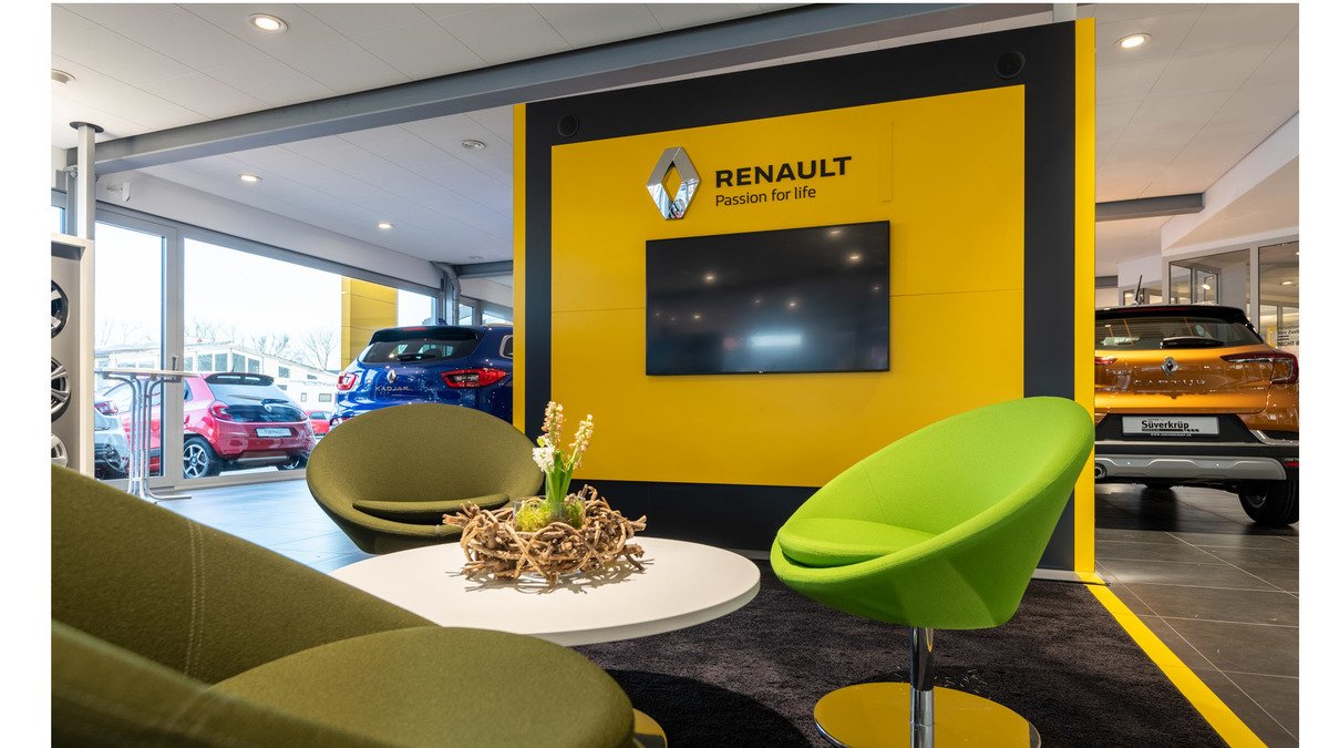 Renault Showroom mit grünen Sesseln, Bildschirm und Autos im Hintergrund, Markenlogo