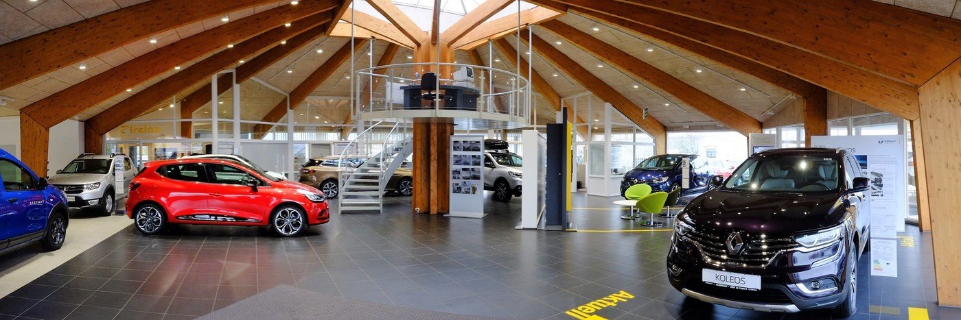 Moderne Autohandlung mit verschiedenen Fahrzeugen, Holzoptik und heller Beleuchtung, + Galerieebene.