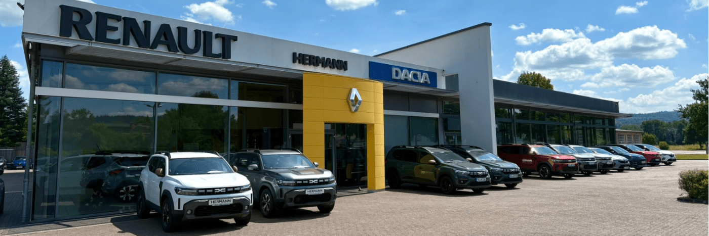 Renault und Dacia Autohaus mit verschiedenen Fahrzeugen bei sonnigem Wetter und blauem Himmel.