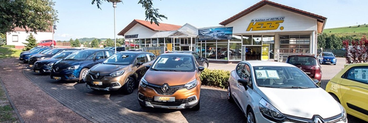 Autohaus mit einer Reihe von Renault-Fahrzeugen auf dem Parkplatz und dem Verkaufsgebäude im Hintergrund.