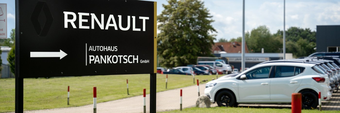 Schild von Renault Autohaus Pankotsch GmbH mit Richtungspfeil und Parkplatz für Autos.