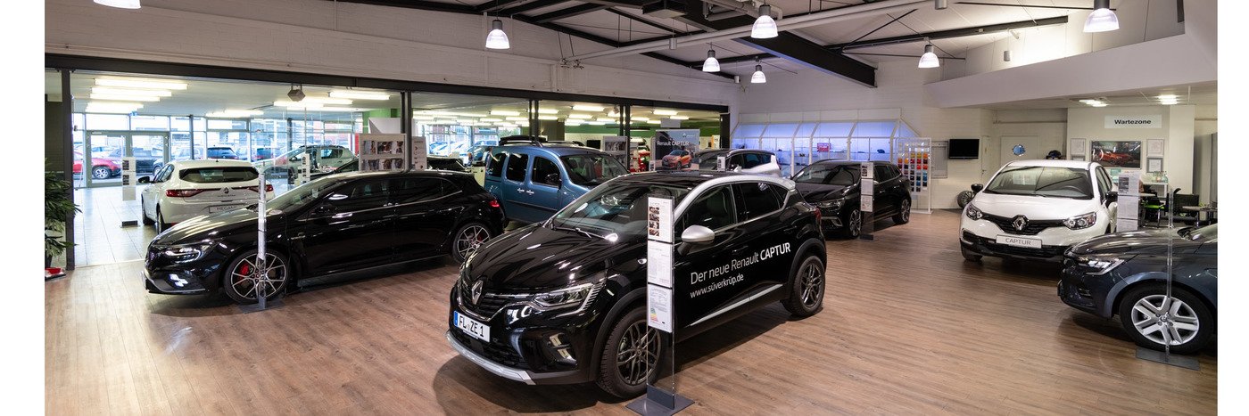 Ein Autohaus-Innenraum mit verschiedenen Autos, darunter schwarze Modelle und ein Renault Captur, gut beleuchtet und modern.