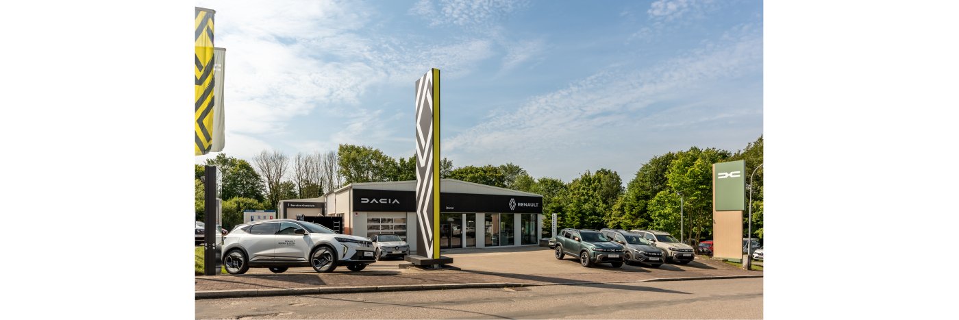 Autohändler mit Dacia und Renault Fahrzeugen vor einem modernen Verkaufsgebäude, umgeben von Bäumen.