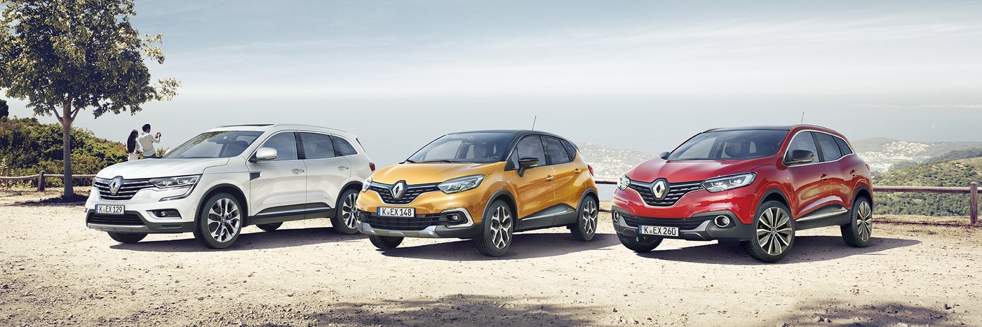 Drei Renault Autos stehen in einer Landschaft: ein weißer SUV, ein orangefarbenes Kompaktmodell und ein roter SUV.