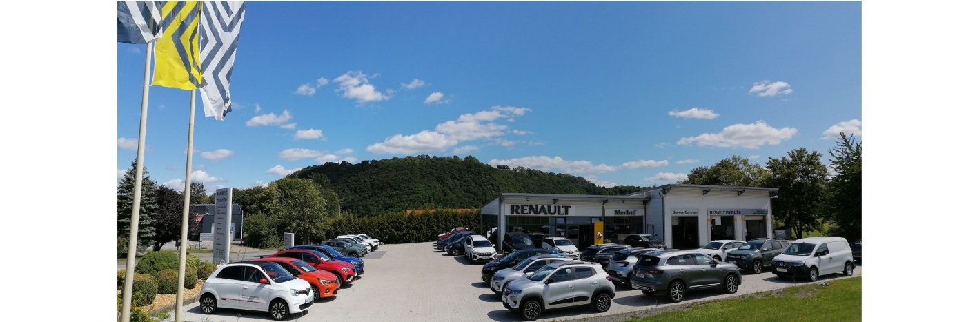Renault Autohaus mit mehreren Autos auf dem Parkplatz und blauen Himmel im Hintergrund.