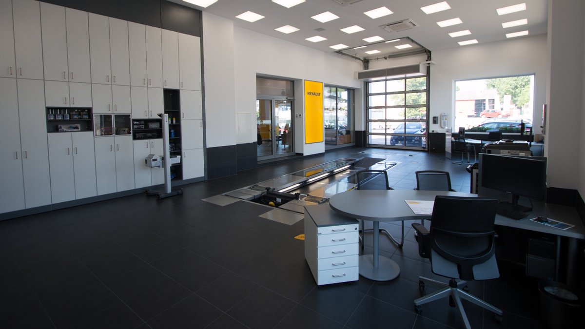 Moderne Werkstatt mit Arbeitsplätzen, Hebebühne und Kundenbereich in einem Autohaus.