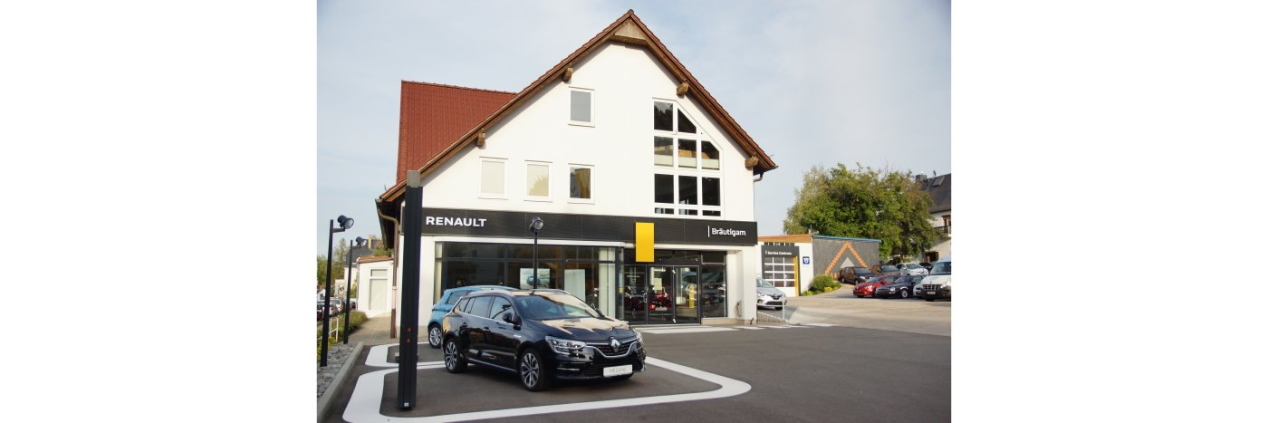 Renault Autohaus mit schwarzem Auto vor dem Gebäude, in einer lichtdurchfluteten Umgebung.