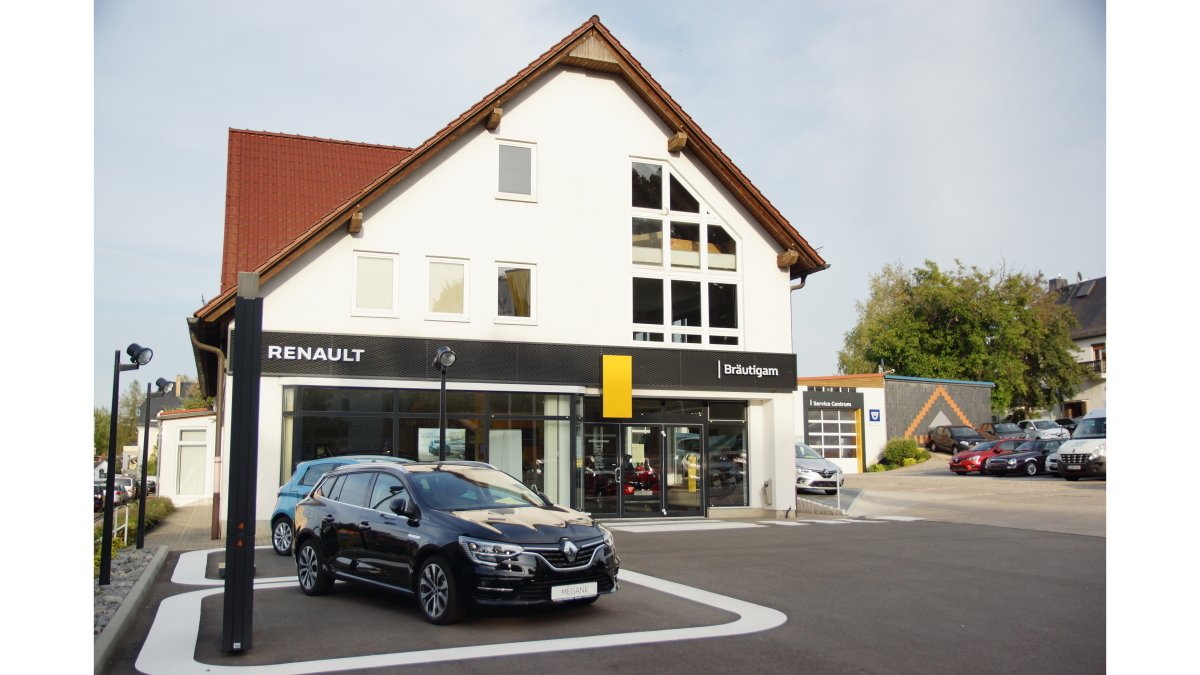 Renault Autohaus mit modernen Fahrzeugen auf dem Parkplatz und schöner Architektur im Hintergrund.