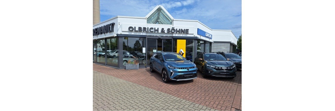 Autohaus Olbrich & Söhne mit mehreren Autos und einer modernen Verkaufsfläche im Freien.