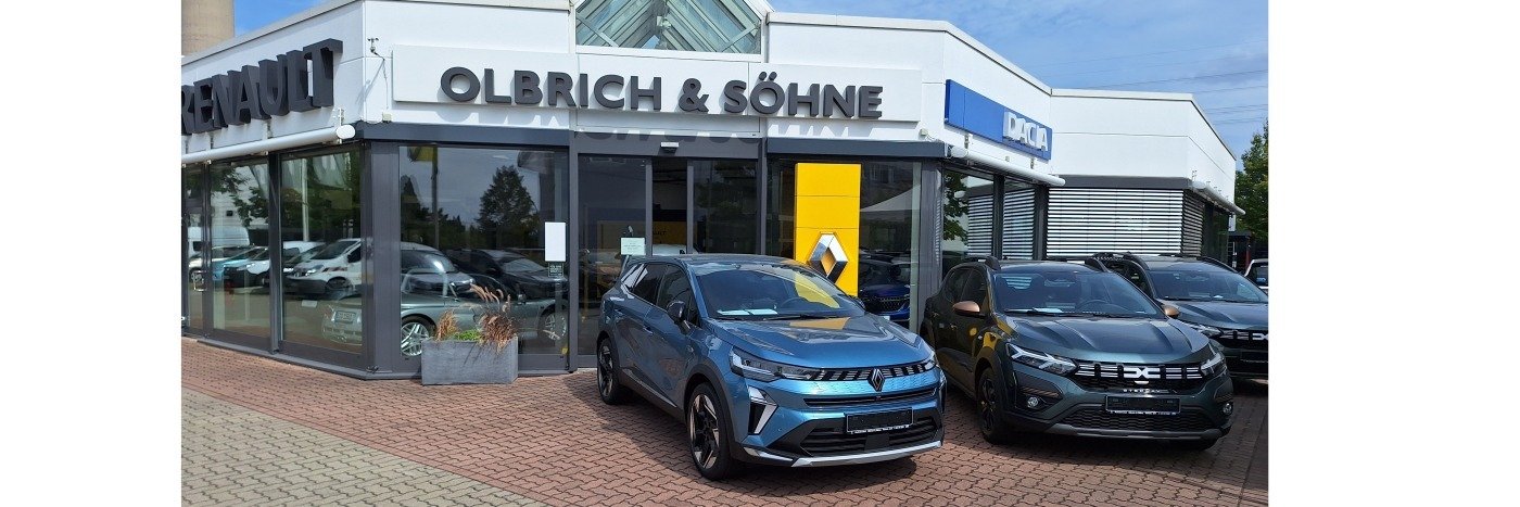 Renault-Autohaus Olbrich & Söhne mit einem blauen SUV und einem schwarzen Dacia im Vordergrund.
