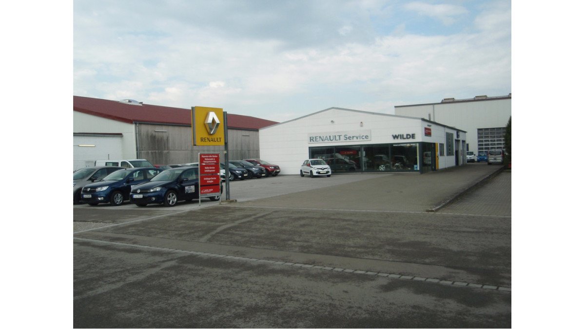 Renault-Servicezentrum mit Autos auf dem Parkplatz und großem Firmengebäude in der Nähe.
