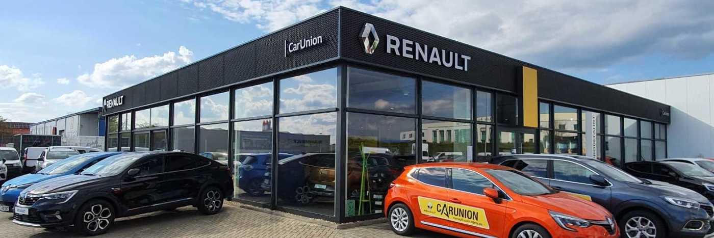 Renault Autohaus mit bunten Autos auf dem Parkplatz unter blauem Himmel.