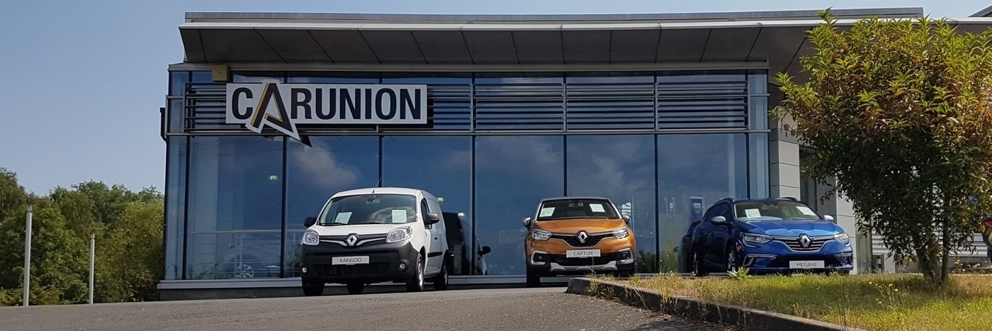 Renault-Autos stehen vor einem modernen Autohaus mit der Beschriftung CARUNION.