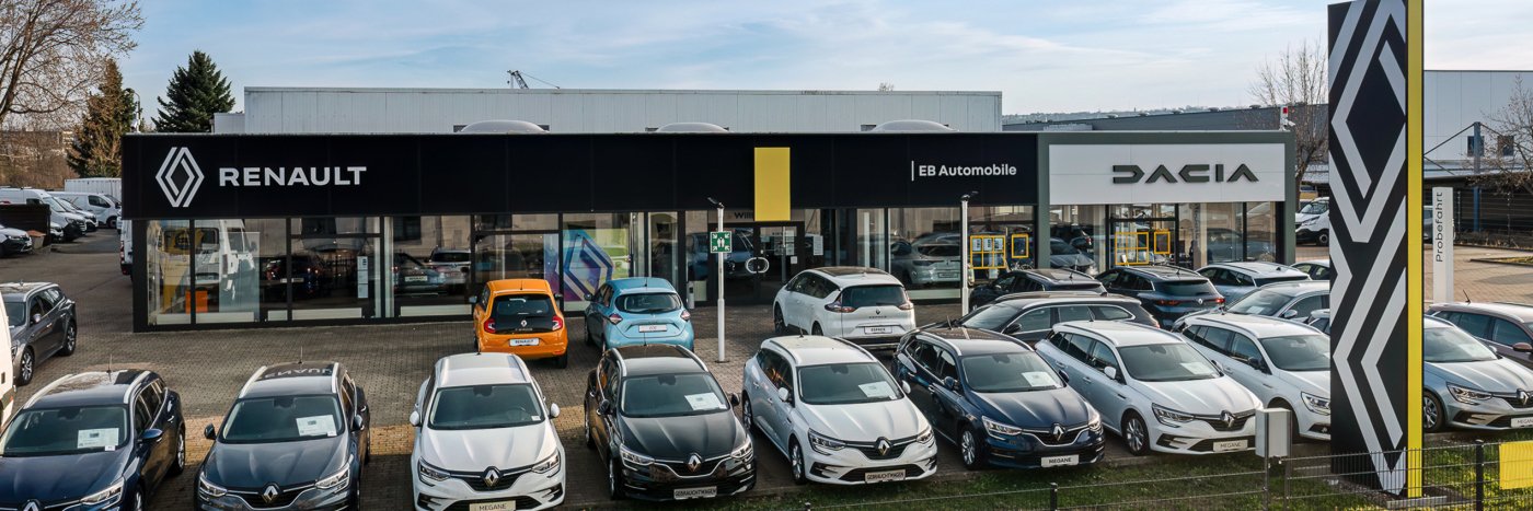 Renault und Dacia Autohaus mit einer Auswahl an Fahrzeugen auf dem Parkplatz.