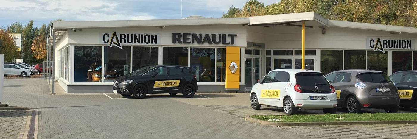 Renault Autohaus CarUnion mit mehreren Autos und Glasfassade, bei hellem Wetter, Parkplatz im Vordergrund.