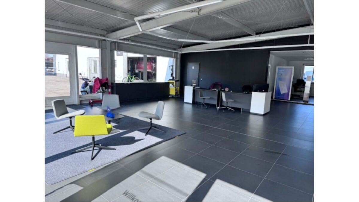 Moderne Büroumgebung mit Sitzgelegenheiten, Schreibtisch und großen Fenstern. Helle, offene Raumgestaltung.