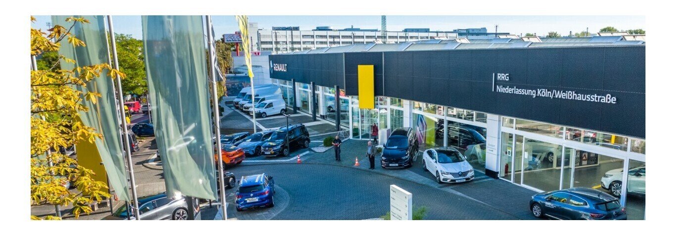 Renault Händler in Köln mit mehreren Autos vor dem Eingang, Flaggen im Vordergrund.