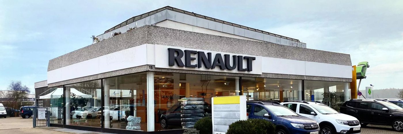 Renault Autohaus mit großer Glasfront, moderner Architektur und ausgestellten Fahrzeugen auf dem Parkplatz.