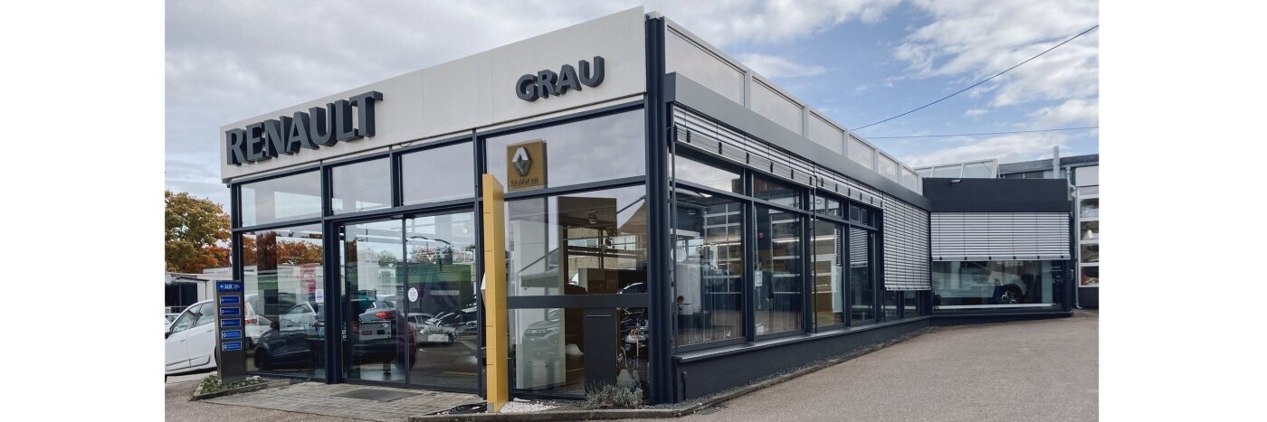Renault Grau Autohaus: modernes Gebäude mit großen Fenstern und gelber Renault-Logosäule.