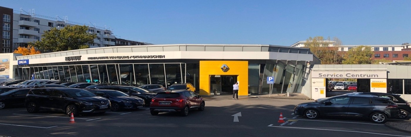 Renault Autohaus mit modernem Design, Parkplatz und Servicezentrum. Mehrere Autos im Vordergrund.