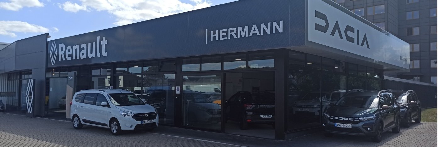 Renault und Dacia Autohaus Hermann mit weißen und schwarzen Autos vor der modernen Glasfassade.