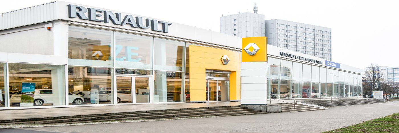 Renault Autohaus mit großen Glasfenstern und dem Renault Logo in gelber Farbe, umgeben von moderner Architektur.