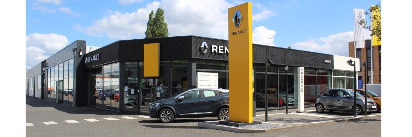 Renault Autohaus mit modernen Glasfassaden und gelbem Logo, Parkplätze und mehrere Fahrzeuge sichtbar.