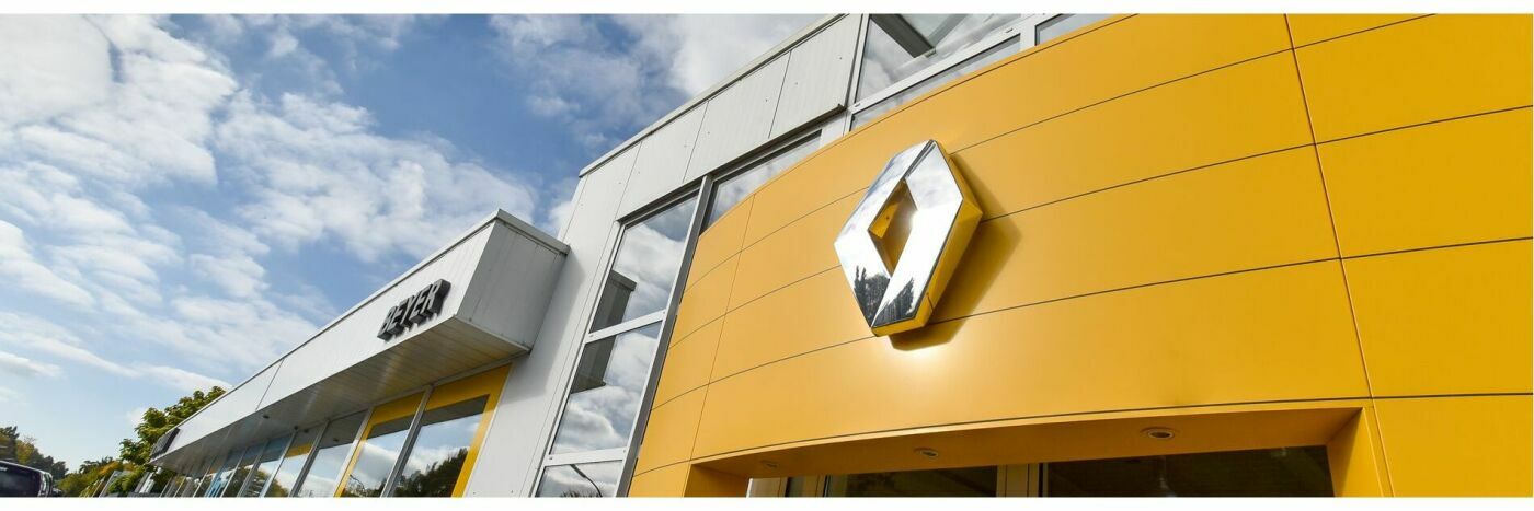 Renault-Filiale mit gelbem Logo und moderner Architektur unter blauem Himmel.