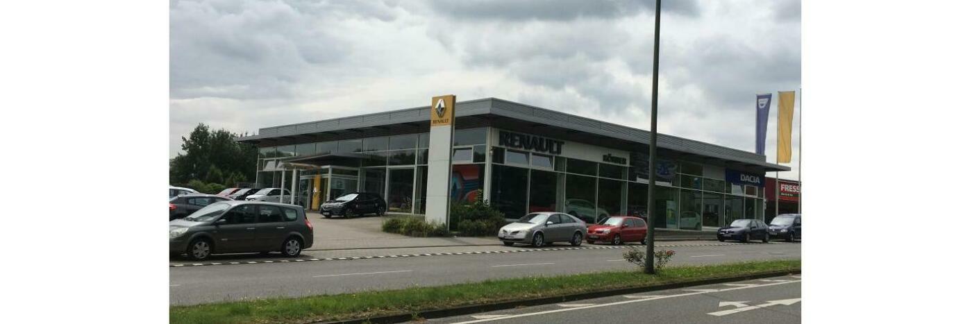 Renault Autohaus mit modernen Fahrzeugen und gedecktem Parkplatz an einer Hauptstraße.