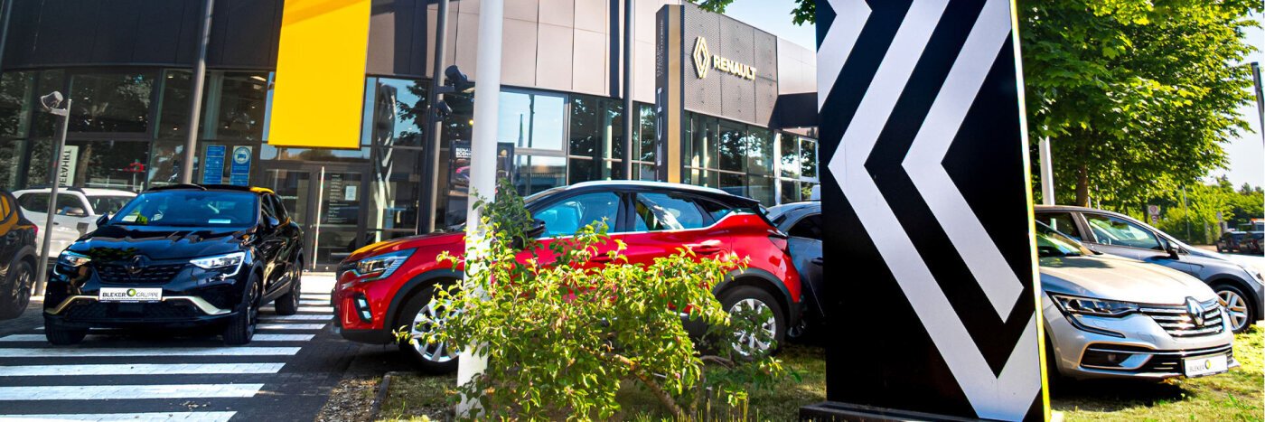 Renault Autohaus mit verschiedenen Fahrzeugen, darunter ein rotes SUV, vor einem modernen Gebäude.