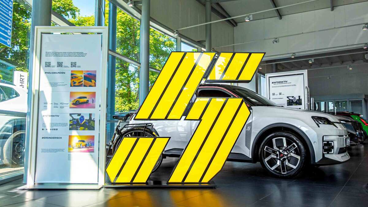 Ein gelbes, stylisches Display in Form einer Zahl steht neben einem modernen Auto in einem Ausstellungsraum.