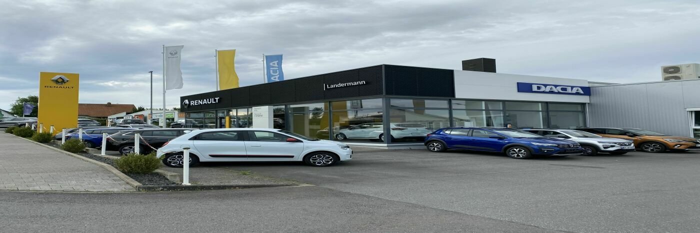 Renault und Dacia Autohaus mit Autos vor dem Gebäude und Fahnen in der Umgebung.