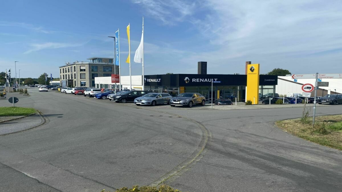 Renault Autohaus mit mehreren Autos auf dem Parkplatz und fließendem Verkehr in der Umgebung.