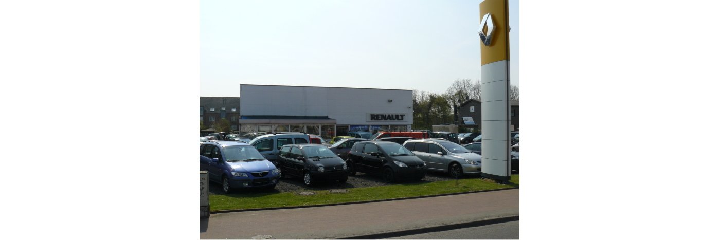 Renault-Autohaus mit zahlreichen geparkten Autos auf dem Gelände, sonniger Tag.