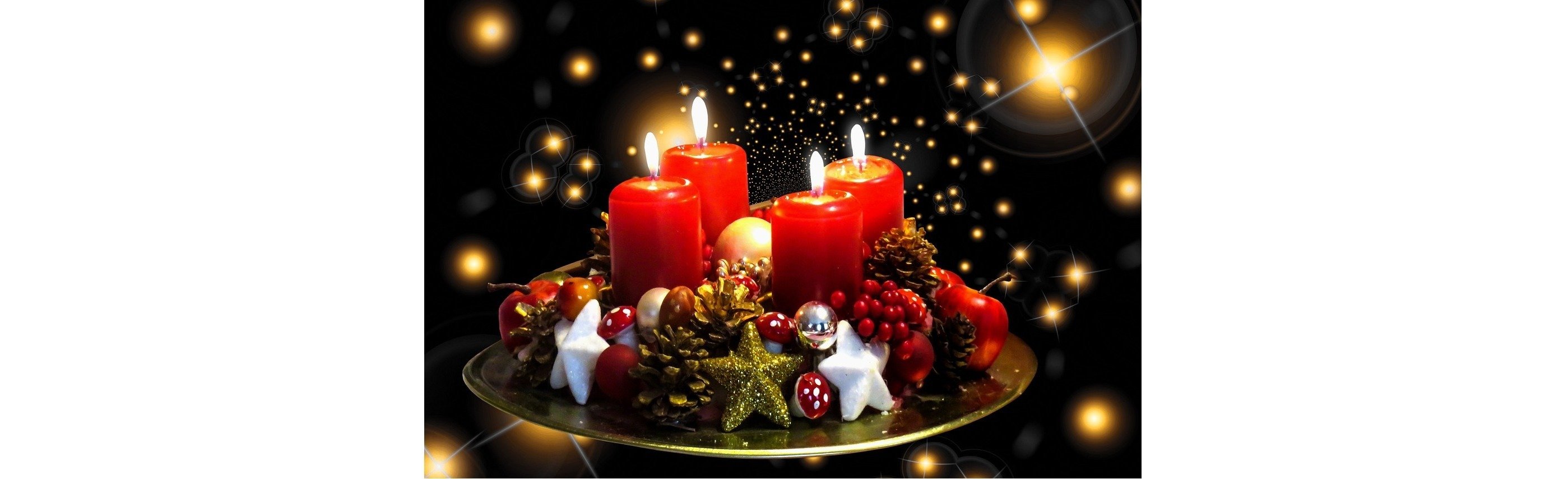 Weihnachtliche Dekoration mit roten Kerzen, Tannenzapfen, einer goldenen Sternschnuppe und festlichen Kugeln auf einem Tisch.