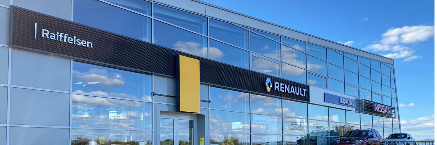 Außenansicht eines Autohändlers mit Renault, Dacia und Nissan Logos, unter klarem Himmel.