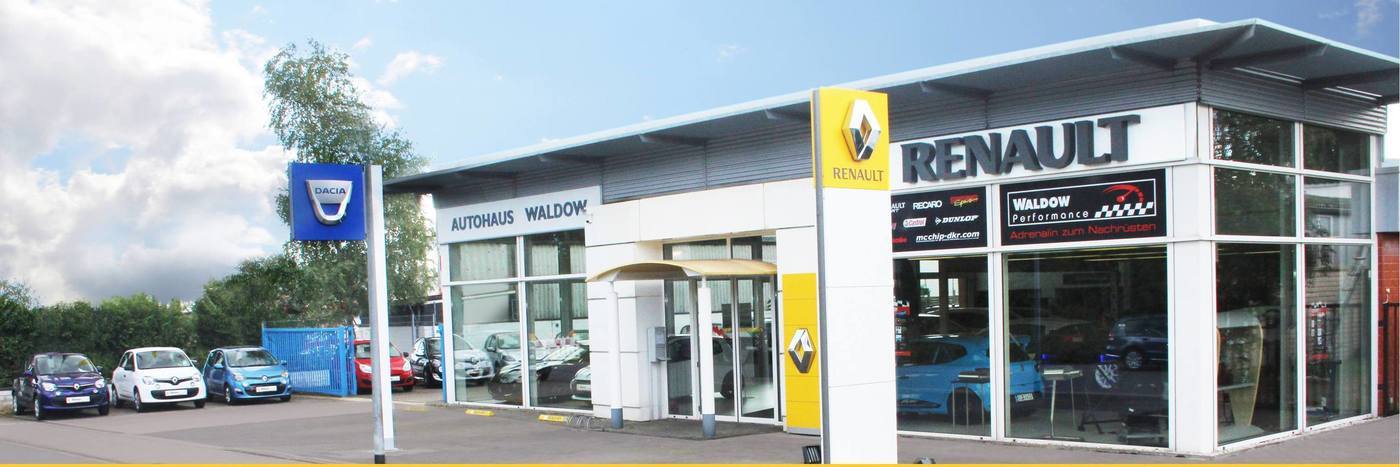 Renault Autohaus Waldow mit mehreren Autos auf dem Parkplatz und Sonnenschein im Hintergrund.